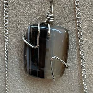 BOTSWANA AGATE PENDANT WRAPPED IN STERLING SILVER WIRE.